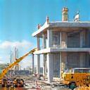 Image representing the active construction management phase on a building site with machinery, workers, and partially completed structure.